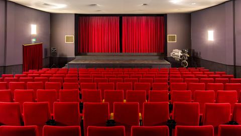 Blick auf rote Stuhlreihen und die Leinwand im Kino Grünberg, die von einem roten Samtvorhang verdeckt wird