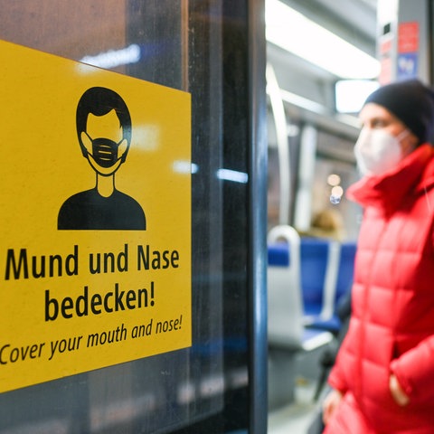 Ein Mann mit Maske steigt in einen Zug.