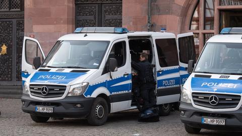 Polizeiautos parken auf einem städtischen Platz. Polizisten stehen neben dem Auto. 