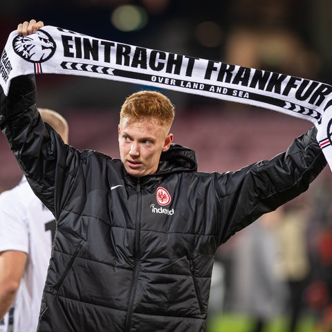 Hugo Larsson hält einen Eintracht-Schal in die Höhe.