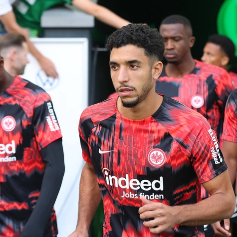 Omar Marmoush im Vordergrund. Die Eintracht-Spieler kommen zum Warmlaufen ins Wolfsburger Stadion.