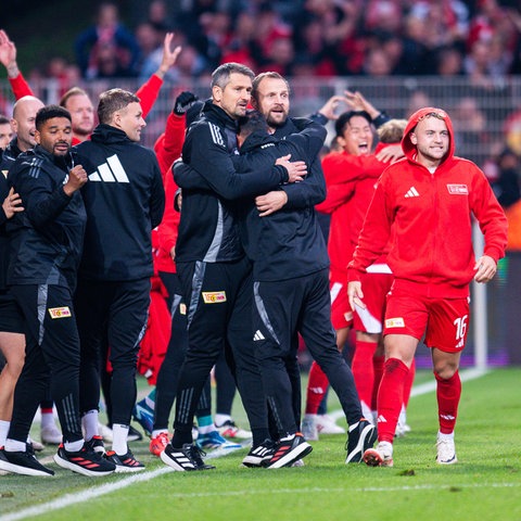 Betreuer und Auswechselspieler von Union Berlin jubeln an der Seitenlinie.