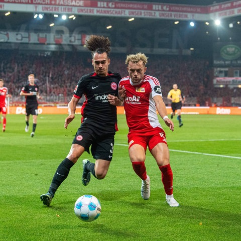 Eintracht Frankfurts Arthur Theate im Duell mit Benedict Hollerbach von Union Berlin