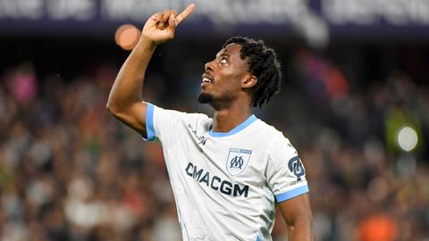 Elye Wahi im Trikt von Olympique Marseille. Zeigt in Richtung des Himmels.